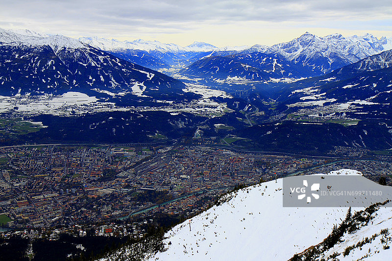 从空中俯瞰奥地利的因斯布鲁克城市全景和田园诗般的北蒂罗尔雪山卡温德尔山脉图片素材