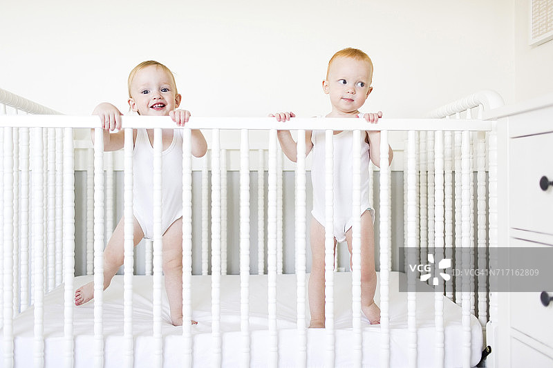 双胞胎兄弟(12-17个月)站在婴儿床上图片素材