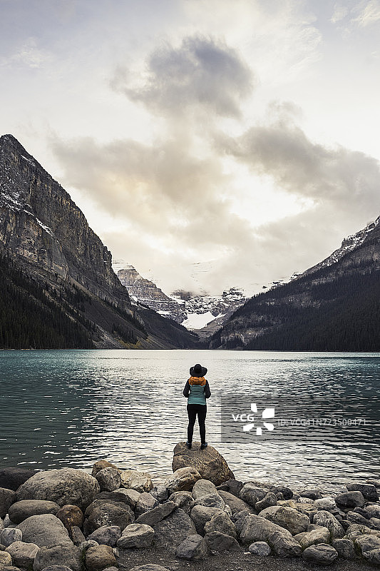 女人站在岩石上，看湖景，后视图，路易斯湖，阿尔伯塔，加拿大图片素材