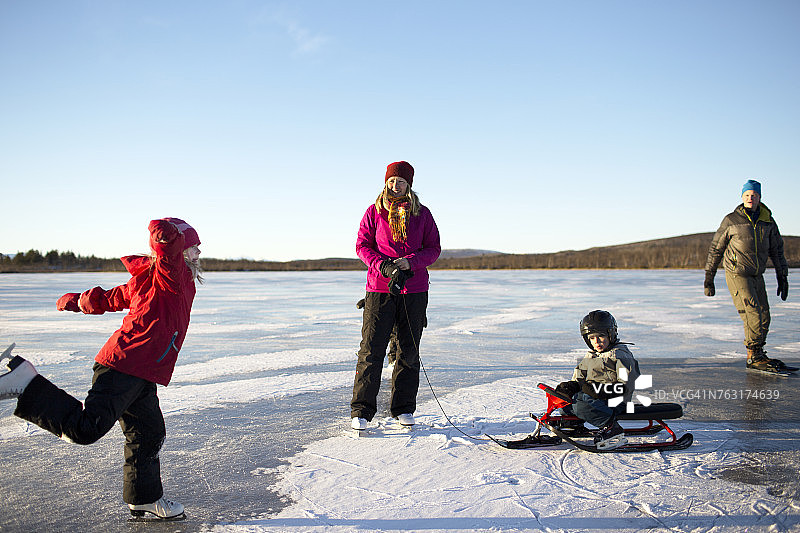 母亲带着孩子们在湖上滑冰图片素材
