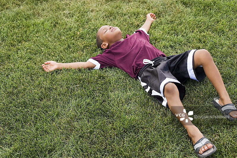 穿着足球服的孩子躺在草地上图片素材
