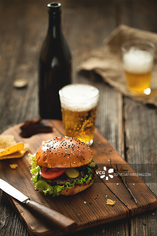 木桌上放着汉堡、沙拉和一杯啤酒。图片素材