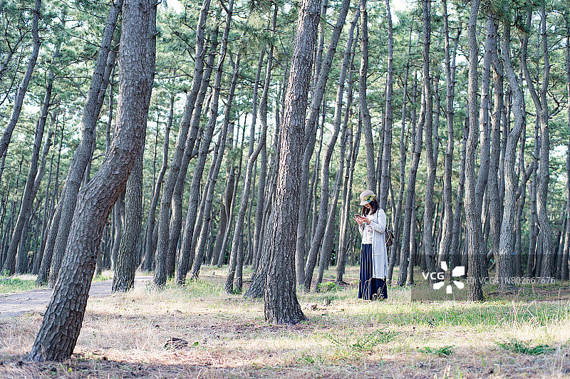 一位日本妇女在森林中触摸手机图片素材