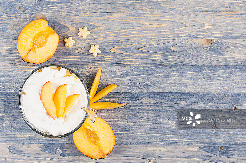 色彩缤纷的早餐配酸奶，星星玉米片，熟桃片放在蓝木板上。带有拷贝空间的装饰边框。图片素材