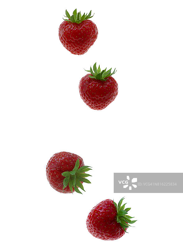 四次草莓落在白色的地上。图片素材