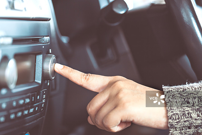 女人开车时用手打开收音机图片素材