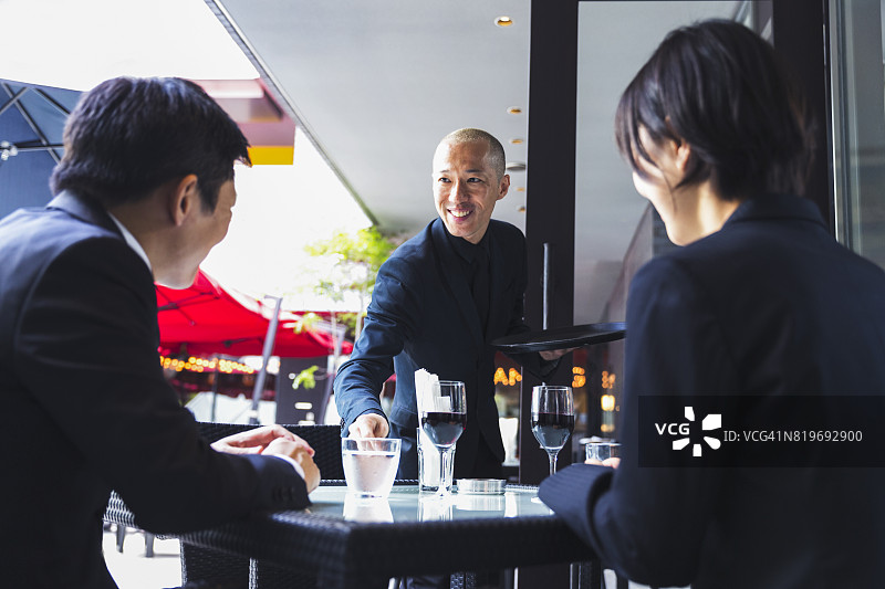 日本服务员微笑着招呼他的顾客，他提供水图片素材