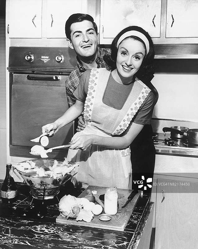 一对夫妇站在厨房里，微笑着，(B&W)图片素材