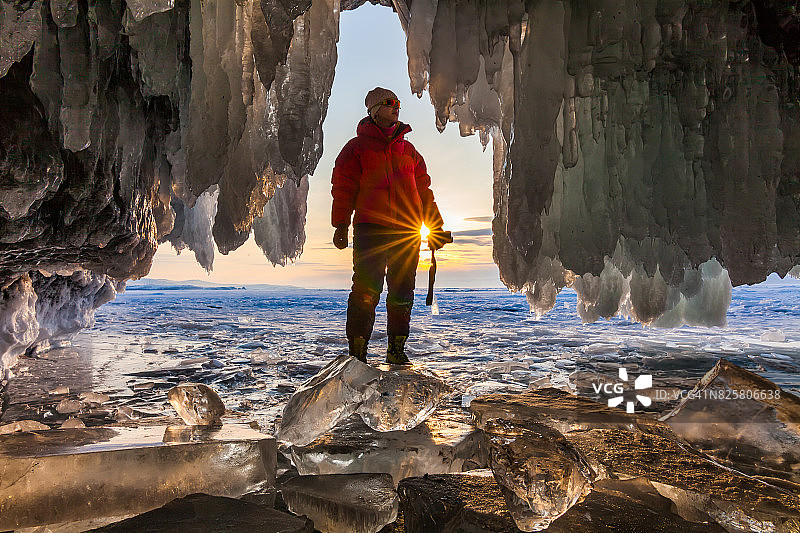 日落时分在冰洞里的探险家。贝加尔湖,俄罗斯图片素材