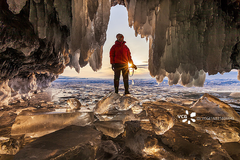 日落时分在冰洞里的摄影师。贝加尔湖,俄罗斯图片素材