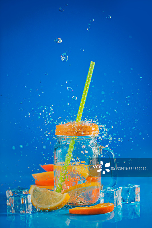 玻璃罐与柠檬水在蓝色背景与水spalsch图片素材