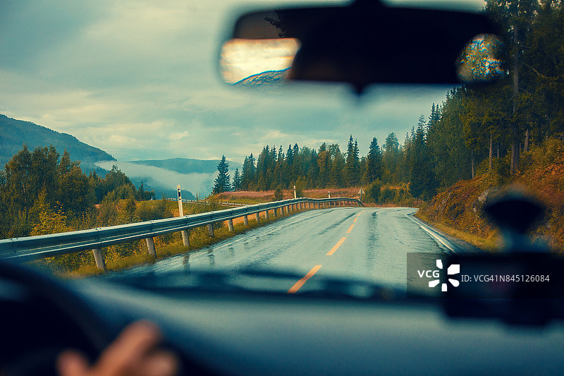 在山路上开车。山路与惊心动魄的暴风雨多云的天空。景观。挪威美丽的大自然。图片素材