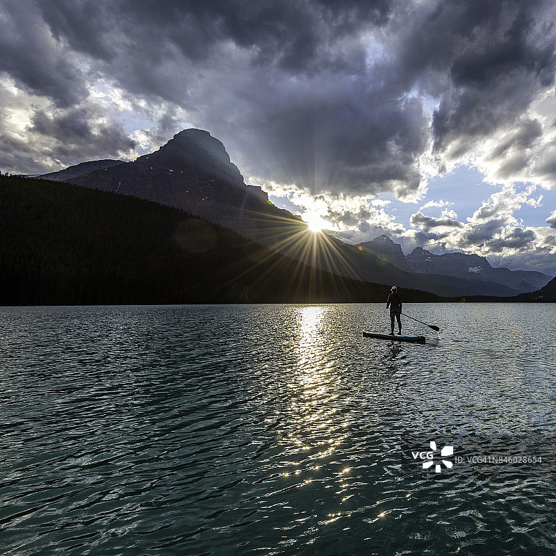 女人划着桨越过高山湖泊，站起来图片素材