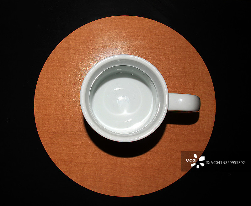 白色陶瓷杯，棕色圆形图案，黑色背景图片素材