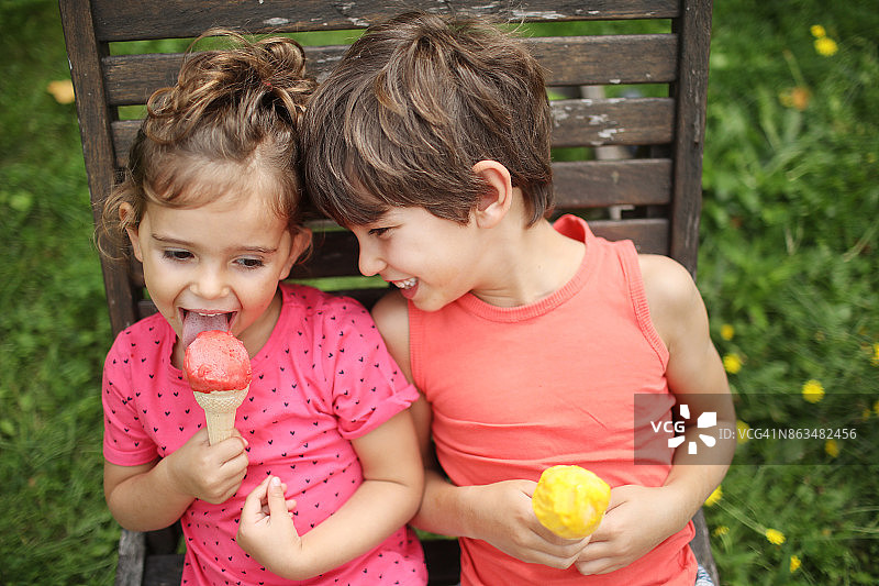 一个哥哥和他的妹妹在花园里吃冰淇淋图片素材