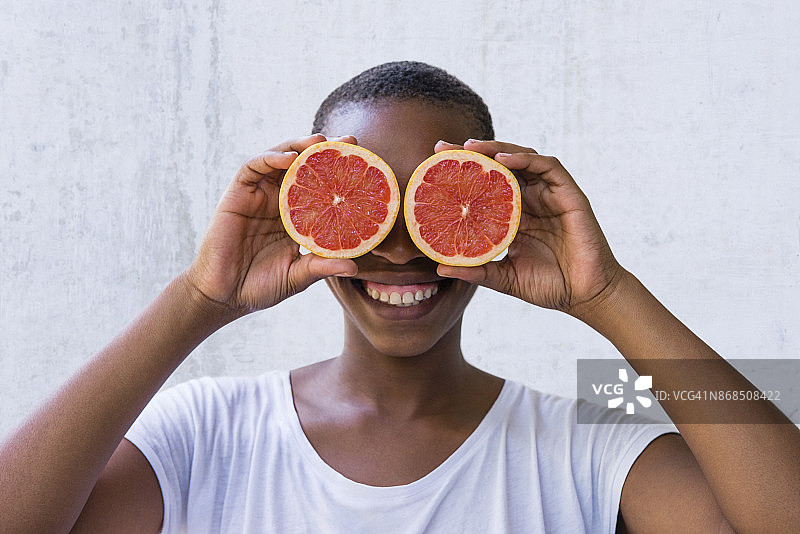 一个年轻女子把葡萄柚放在眼前。图片素材