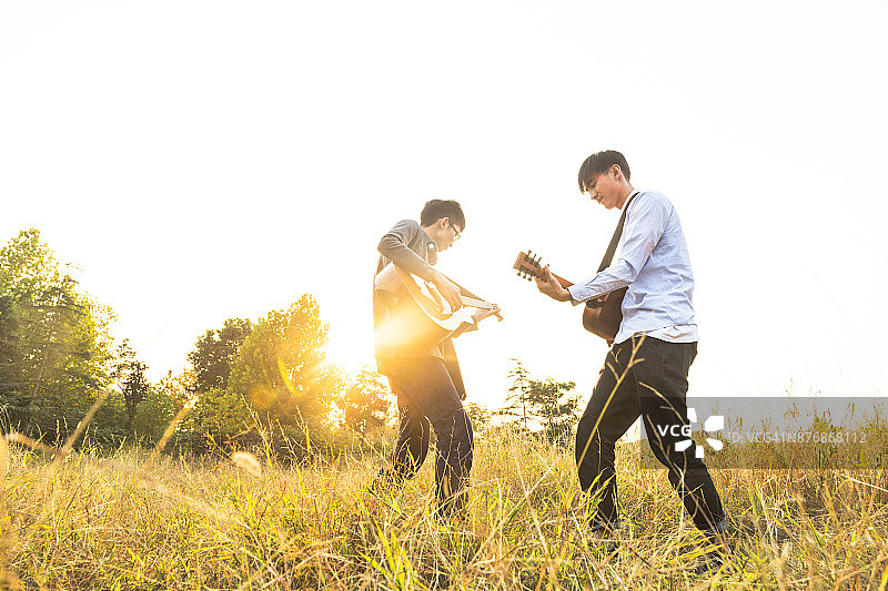 两个男人，朋友在公园草坪上弹吉他图片素材