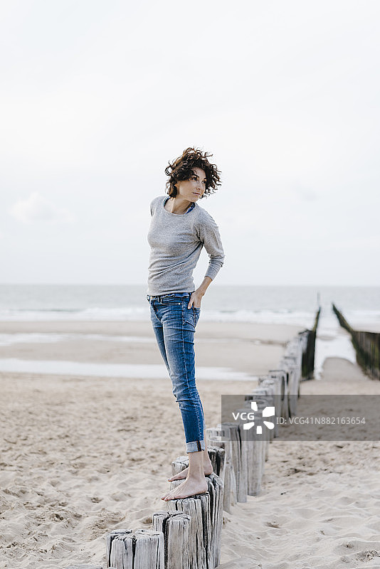 一个女人站在沙滩上的木桩上图片素材