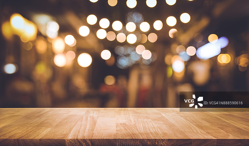 木条桌子与模糊的灯光在夜晚街头咖啡馆图片素材