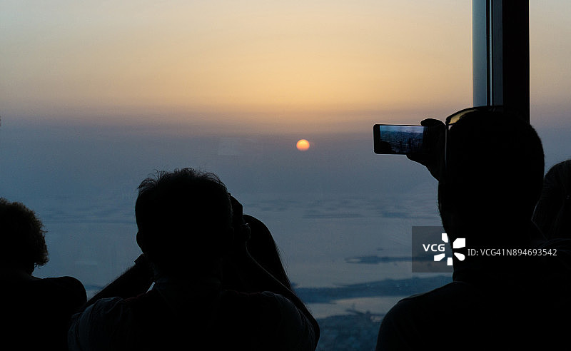阿拉伯联合酋长国迪拜，游客用智能手机拍摄日落的剪影图片素材