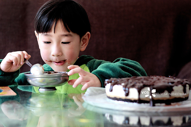 男孩穿着恐龙衣服吃生日蛋糕图片素材