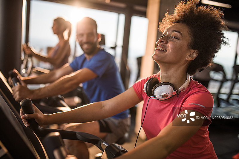 快乐的非裔美国女人享受在健身房里的动感单车课。图片素材
