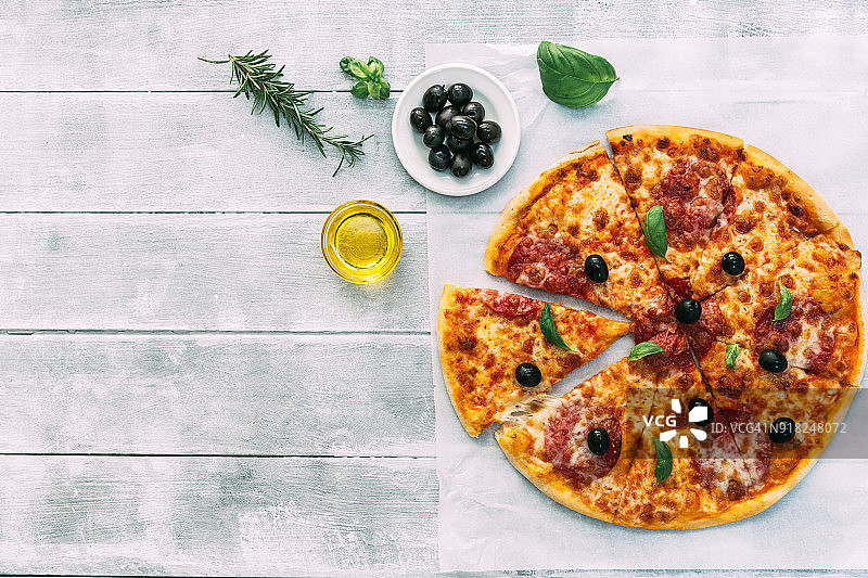 彩色美味的比萨饼，橄榄，意大利辣香肠，火腿和胡椒，切片删除特写镜头，孤立在一个白色的背景图片素材