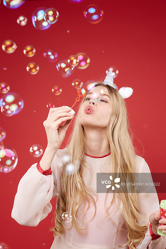 年轻的金发女人吹肥皂泡玩得很开心图片素材