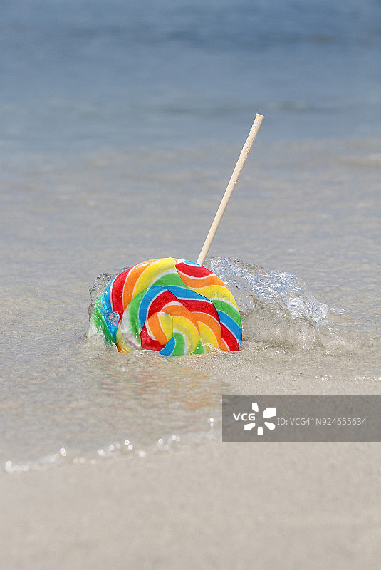 水溅在遗弃在海滩上的彩色棒棒糖上图片素材