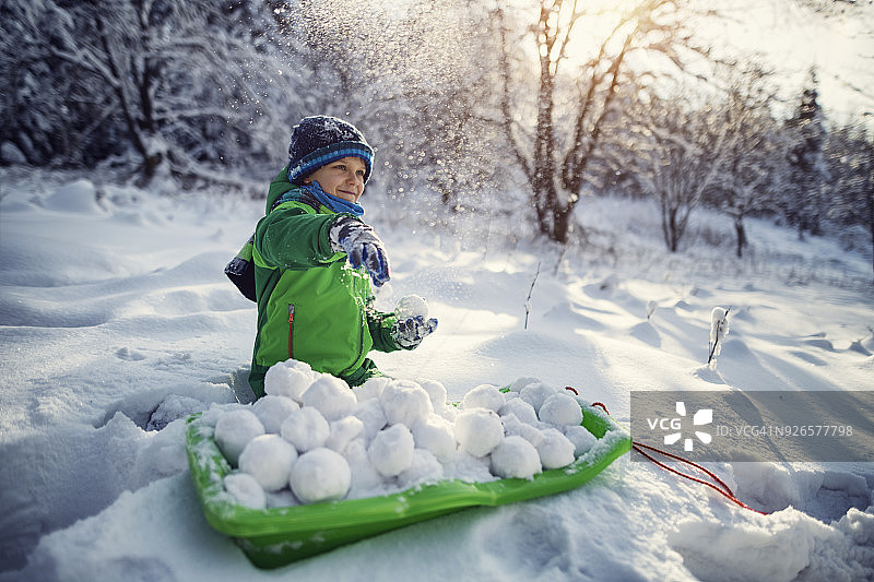 小男孩在冬天的森林里扔雪球图片素材