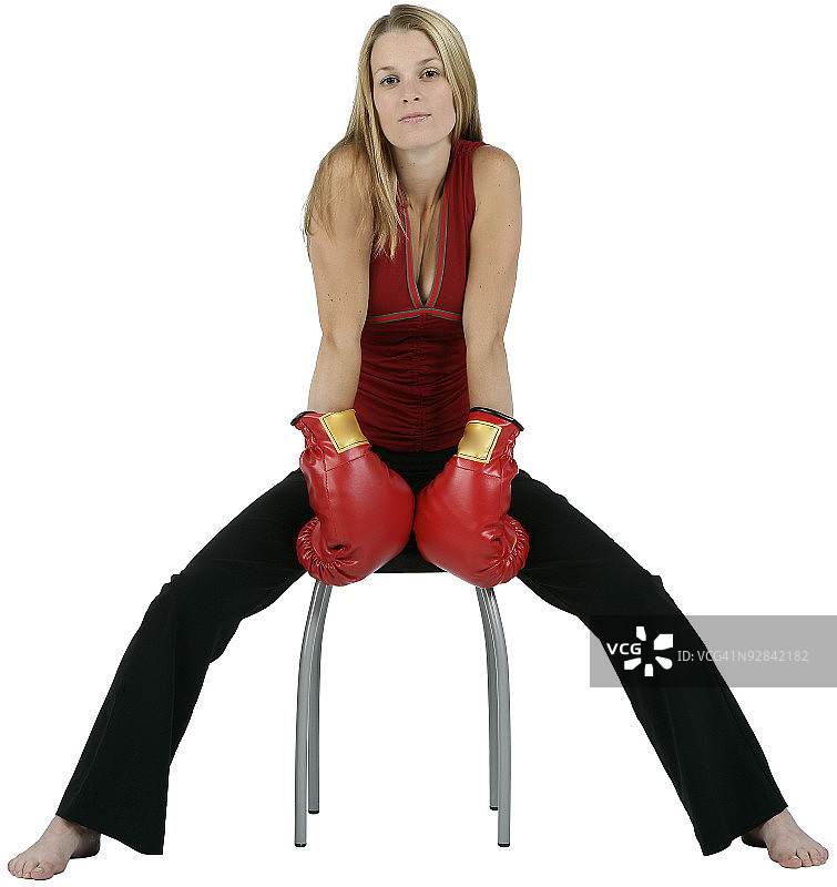 年轻女子摆姿势与拳击手套在椅子上图片素材