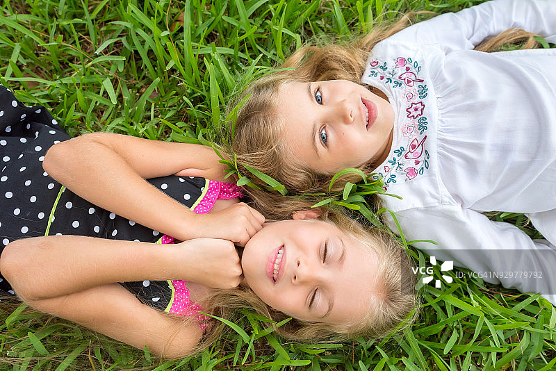 小女孩们摆姿势躺在草地上图片素材