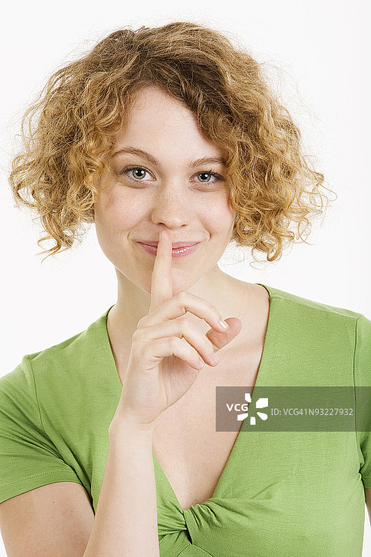 年轻女子手指放在嘴唇上，肖像图片素材