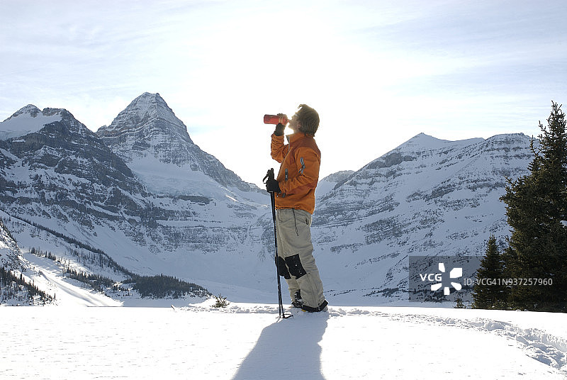 野外滑雪者从水瓶中喝水。图片素材