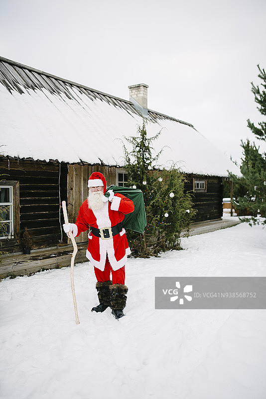 圣诞老人带着礼物来到小木屋旁边图片素材