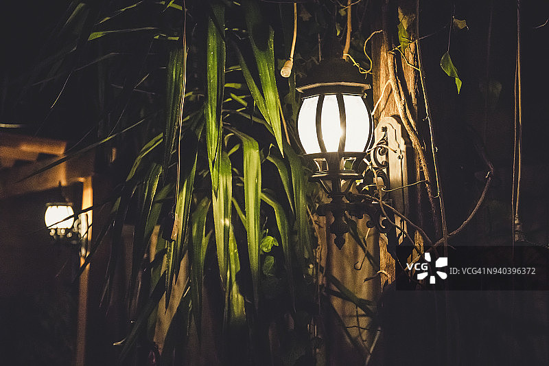 夜晚，在圣安东尼奥河畔步道附近的床上和早餐间，一盏灯在黑暗中照耀。图片素材
