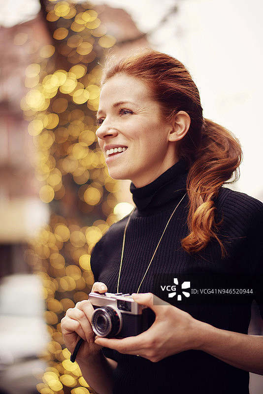 年轻时尚的女性拿着经典相机站在纽约的灯光前图片素材