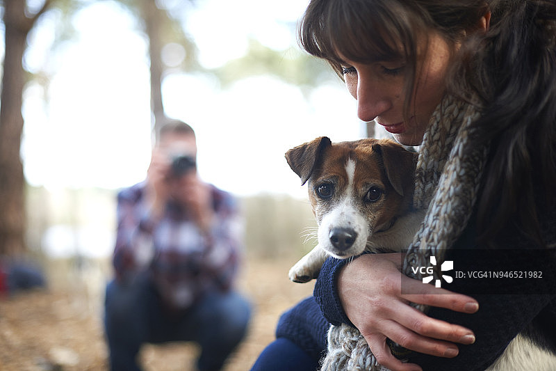 一个男人在树林里给他的女伴和她的狗拍照图片素材