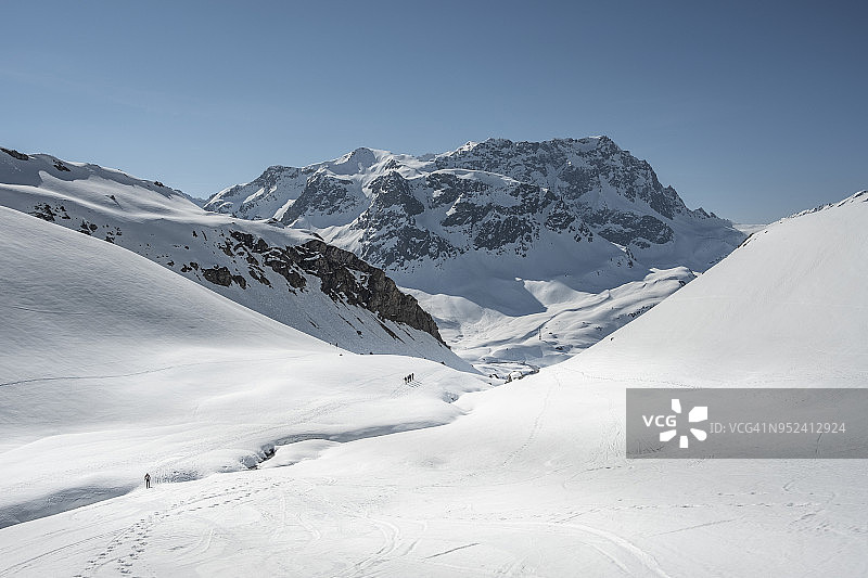 徒步旅行者在白雪覆盖的山谷中行走图片素材