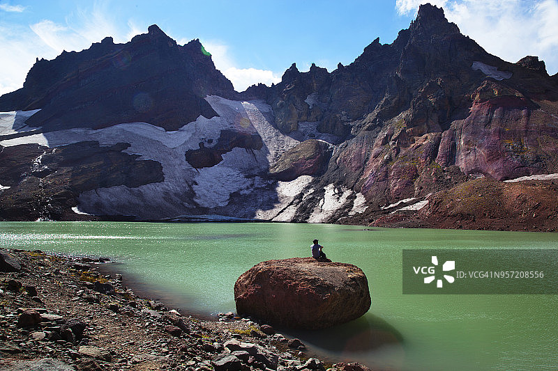 远处的风景，远足者在岩石顶部的湖岸，对着山脉图片素材