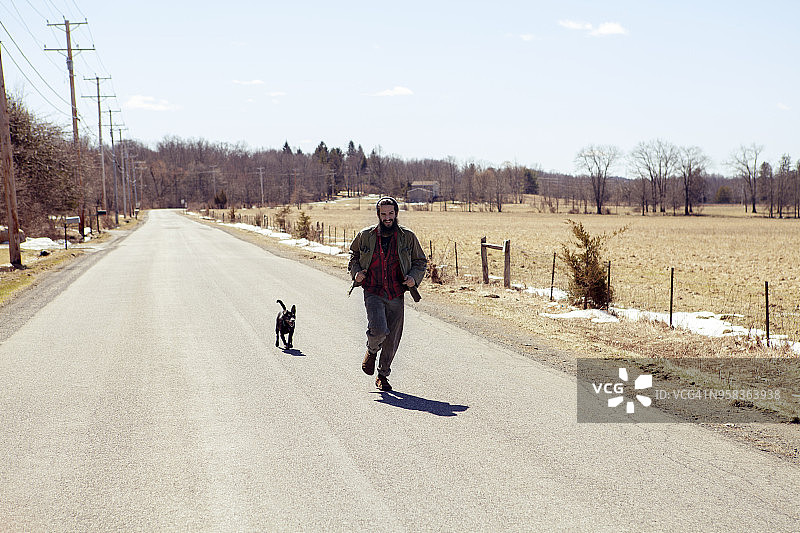 假期的时候，人狗在乡村公路上奔跑图片素材