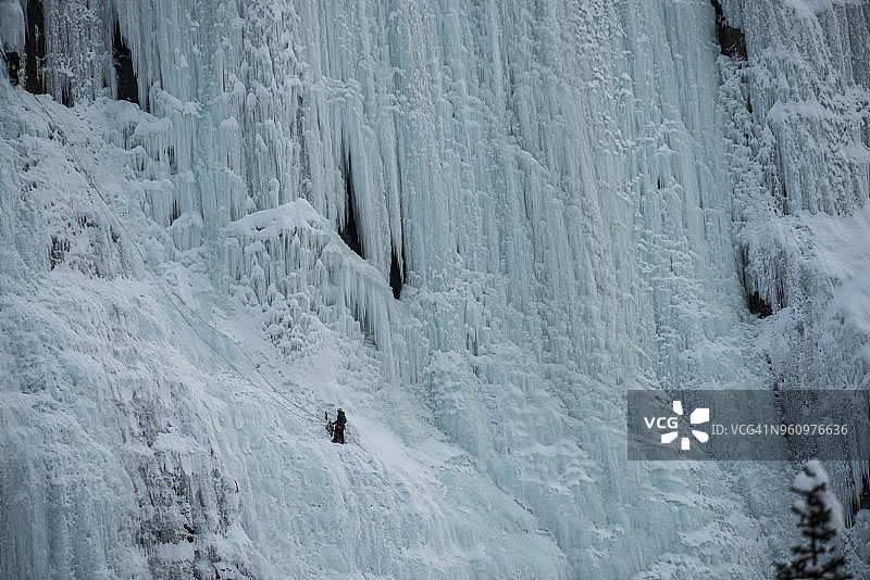 在冰原公园路上，一名徒步旅行者正爬上结冰的渗水墙图片素材
