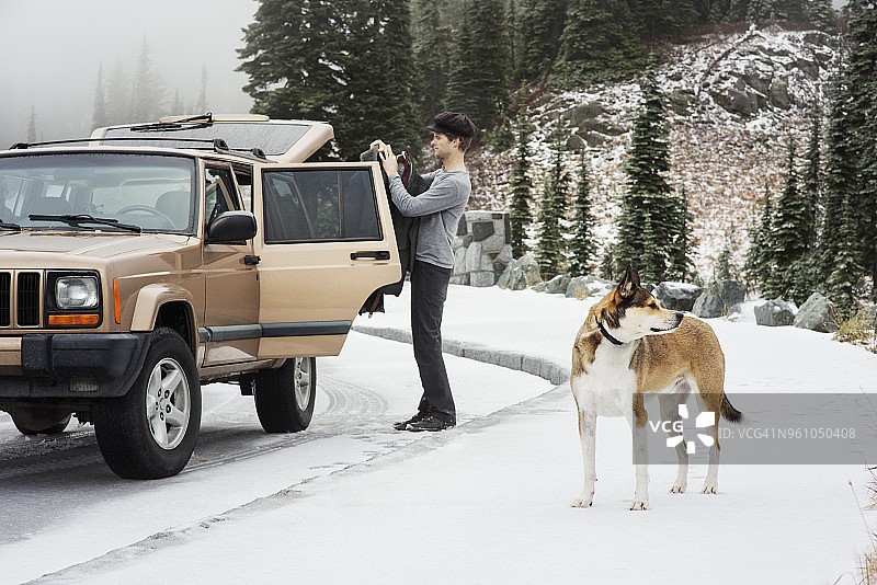 人和狗站在积雪覆盖的街道上的汽车图片素材