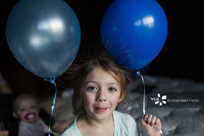 女孩拿着气球站在家里的肖像图片素材
