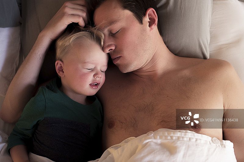 高视角的父亲与儿子睡在床上在家图片素材