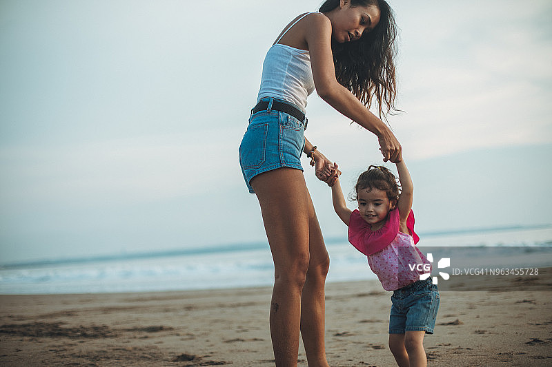 妈妈和可爱的女儿在海滩上玩得很开心图片素材