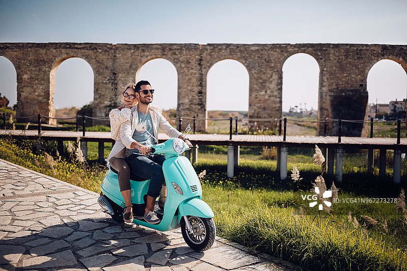一对浪漫的年轻夫妇在意大利小镇上骑着复古机车图片素材