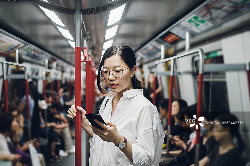 年轻女商人在地铁上看智能手机图片素材