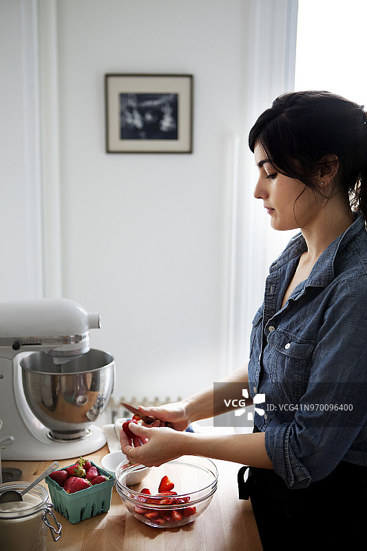 站在厨房里切草莓的女人图片素材