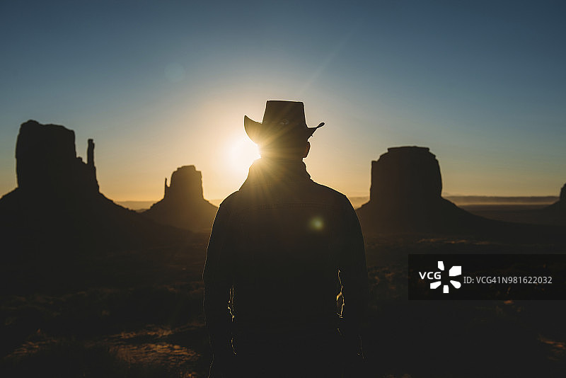 美国犹他州，戴牛仔帽的男子在纪念碑谷欣赏日出图片素材